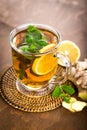 Hot herbal tea with fresh lemon, ginger and mint leaves on brown background, Royalty Free Stock Photo