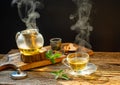 Hot herbal tea in glass teapot and cup with steam on beautiful wooden table