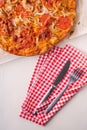 Hot homemade pizza with chicken meat, tomatoes, onions near with cutlery fork and knife on red tablecloth, flat lay, top view Royalty Free Stock Photo