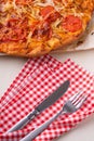 Hot homemade pizza with chicken meat, tomatoes, onions near with cutlery fork and knife on red tablecloth, flat lay, top view Royalty Free Stock Photo