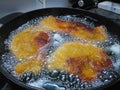 Crispy pork wiener schnitzel frying in hot oil