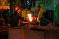 Blacksmith processes the iron product under a huge press, forging metal, stamping. Royalty Free Stock Photo