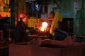 Blacksmith processes the iron product under a huge press, forging metal, stamping. Royalty Free Stock Photo