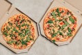 Hot Italian pizzas with arugula in cardboard boxes