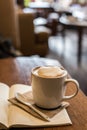 Hot latte art coffee cup on wooden table and note book, vintage Royalty Free Stock Photo