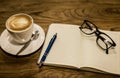 Hot latte art coffee cup on wooden table and note book, vintage Royalty Free Stock Photo