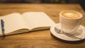 Hot latte art coffee cup on wooden table and note book, vintage Royalty Free Stock Photo