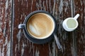 Hot latte coffee in black cup on wooden table- top view