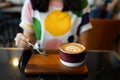 Hot Latte - A cup of coffee with milk and beautiful leaf pattern latte art on wooden table and blurred background. Royalty Free Stock Photo