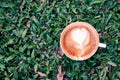 Hot Latte heart shape coffee in white cup on green grass