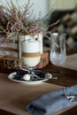 Hot latte macchiato coffee with tasty foam clear glass on dark wooden table serving with cookie,cane sugar. Coffee time Royalty Free Stock Photo