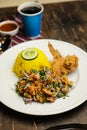 Hot Lemony Chicken Rice Meal served in plate with sauce, cold drink, spoon and fork isolated on wooden board side view of thai