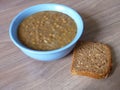 Hot lentil soup in a blue bowl with slife of bread