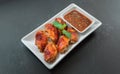 Hot Meat Dishes - Grilled Chicken Wings with Red Spicy Thai style Sauce on black background Royalty Free Stock Photo