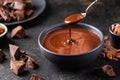 Hot melted chocolate dripping from a spoon into a bowl of chocolate on a dark textured background. Royalty Free Stock Photo