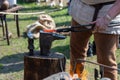 Hot metal red lies on the anvil. The blacksmith forms a knife blade