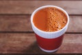 Hot milk tea in a red cup on wooden table blurred background. Royalty Free Stock Photo