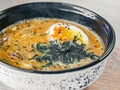 Hot miso soup with cut egg, sesame seeds, nori in black white plate on wood table. Top view, close-up. Japanese cuisine Royalty Free Stock Photo