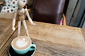 Hot mocha coffee or cappuccino in the green cup with a wood man standing on the wooden table Royalty Free Stock Photo