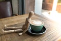 Hot mocha coffee or capuchino in the green cup lean by wood man on the wooden table Royalty Free Stock Photo