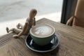 Hot mocha coffee or capuchino in the green cup lean by wood man on the wooden table Royalty Free Stock Photo