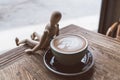 Hot mocha coffee or capuchino in the green cup lean by wood man on the wooden table Royalty Free Stock Photo