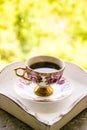 Hot morning coffee in small floral design cup with gold on shabby chic vintage white tray on window sill in front of summer window Royalty Free Stock Photo