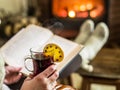 Hot mulled wine and book in woman hands. Royalty Free Stock Photo