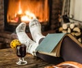 Hot mulled wine and book in woman hands. Relaxing in front of burning fire in the cold winter day Royalty Free Stock Photo