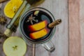 Hot mulled wine drink with lemon, apple, cinnamon, anise and other spices in a glass cup between fir tree branches on wooden Royalty Free Stock Photo