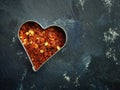 Hot organic chili flakes in a heart shaped cookie cutter, top view Royalty Free Stock Photo