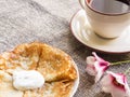 Hot pancakes on a plate with sour cream and a cup of tea Royalty Free Stock Photo