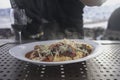 Hot pasta on a white plate, wine glass, blurred person in the background. Royalty Free Stock Photo