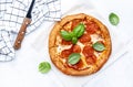 Hot pepperoni pizza with spicy salami sausage, mozzarella cheese, tomato sauce and green basil, white table background, top view