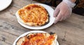 A hot pizza just coming out of a rustic outdoor bread oven.