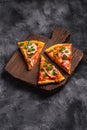 Hot pizza slices with mozzarella cheese, ham, tomato and parsley on brown wooden cutting board