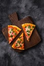 Hot pizza slices with mozzarella cheese, ham, tomato and parsley on brown wooden cutting board