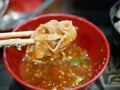Hot-pot thin pork slice being dipped in Sukiyaki sauce