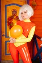 Hot pretty blonde woman in bright colorful latex rubber catsuit ready for halloween autumn party and posing with air Royalty Free Stock Photo