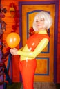 Hot pretty blonde woman in bright colorful latex rubber catsuit ready for halloween autumn party and posing with air