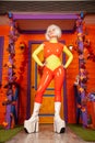 Hot pretty blonde woman in bright colorful latex rubber catsuit ready for halloween autumn party and posing near her Royalty Free Stock Photo