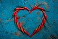 Hot red chili pepper in the shape of a heart on a blue wooden table Royalty Free Stock Photo