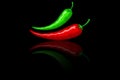 Hot mexican peppers. Green and red peppers on the black background with mirror reflection