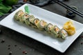 Hot roll with salmon and eel on white plate on dark stone table Royalty Free Stock Photo