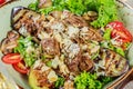 Hot salad with veal, mushrooms, salad leaves, eggplant, zucchini, tomatoes, garnished with grated almonds and Parmesan cheese Royalty Free Stock Photo