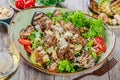 Hot salad with veal, mushrooms, salad leaves, eggplant, zucchini, tomatoes, garnished with grated almonds and Parmesan cheese and Royalty Free Stock Photo