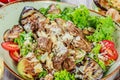 Hot salad with veal, mushrooms, salad leaves, eggplant, zucchini, tomatoes, garnished with grated almonds and Parmesan cheese Royalty Free Stock Photo