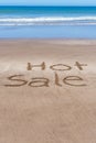 Hot Sale written in the sand of the beach on the seashore. Royalty Free Stock Photo