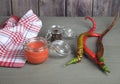 Hot sauce in a jar of red pepper on a gray wooden background, pepper pods