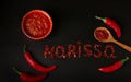 Hot sauce paste harissa with chili pepper on dark background, Tunisia and Arabic cuisine, word Harissa of Dry pepper